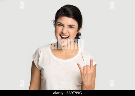 Colpo alla testa ritratto sorridente ragazza indiana che mostra cool rock gesto Foto Stock