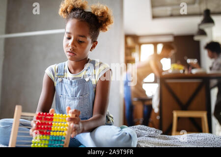 Felice African American kid girl imparare a contare a casa con abacus Foto Stock