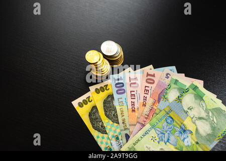 Il concetto di business, valuta rumena sulla tavola nera. LEI banconote e monete Foto Stock
