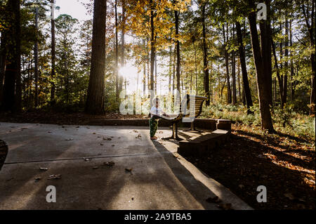 Carino il toddler in piedi accanto al banco a tramonto Foto Stock