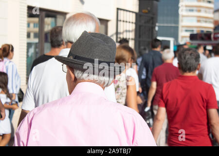 Il vecchio uomo a camminare sulla strada con una fedora. Vecchio classico abbigliamento con stile. Foto Stock