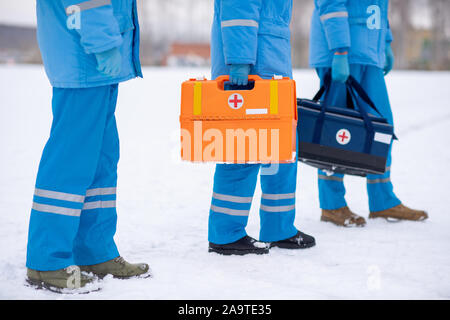 Sezione bassa del personale paramedico in uniforme blu e guanti azienda kit di primo soccorso Foto Stock