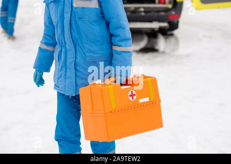 Giovane paramedico in workwear portando il kit di primo soccorso mentre andando al malato Foto Stock