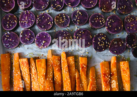 Fette di viola le patate dolci cosparsi di semi di sesamo e le carote affettate Foto Stock