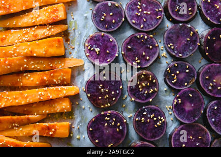 Fette di viola le patate dolci cosparsi di semi di sesamo e carote Foto Stock