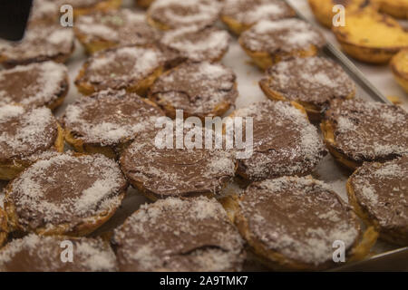Ricoperta di cioccolato Crema pasticcera crostate (chiamato anche Pasteis de nata) in una pasticceria a Lisbona. Foto Stock