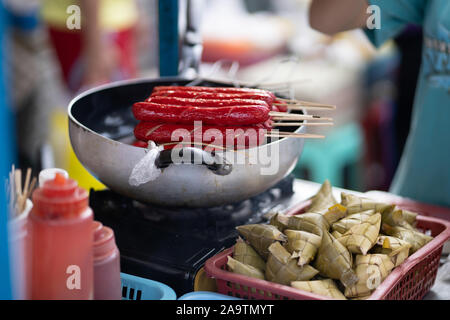 Salsicce di rosso su un bastone normalmente brace sono un popolare snack alimentare nelle Filippine,noto come hot dogs. Foto Stock