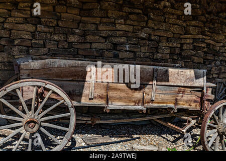 Un antica fattoria buckboard carro si siede di fronte a un muro di pietra nel sud dell'Idaho. Foto Stock