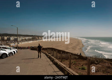 Vista posteriore di uomo che guarda a sud lungo la passerella a Ocean Beach. San Francisco, CA, Stati Uniti d'America. Sep 2019 Foto Stock