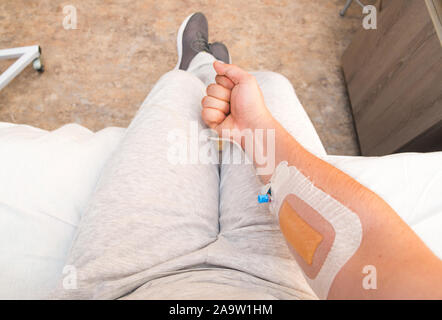 Mano del paziente con il pugno con catetere di infusione. Prospettiva in prima persona Foto Stock