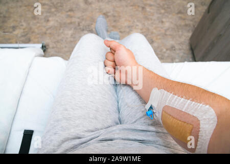 Mano del paziente con il pugno con catetere di infusione. Prospettiva in prima persona Foto Stock