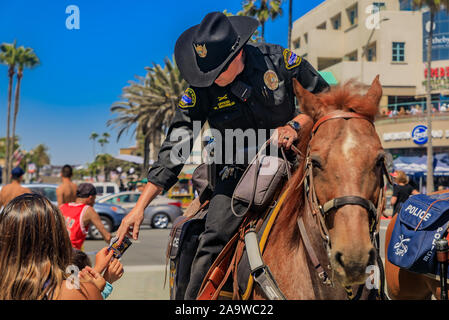 Huntington Beach, Stati Uniti d'America - Luglio 03, 2017: Equestre degli ufficiali di polizia da Huntington Beach e Santa Ana i dipartimenti di polizia di interagire con i turisti Foto Stock