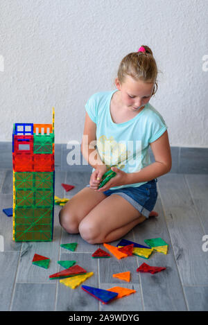 Bella ragazza adolescente giocando con un sacco di colorati di materia plastica in blocchi costruttore e costruisce la casa. Foto Stock