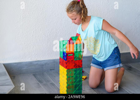 Bella ragazza adolescente giocando con un sacco di colorati di materia plastica in blocchi costruttore e costruisce la casa. Foto Stock