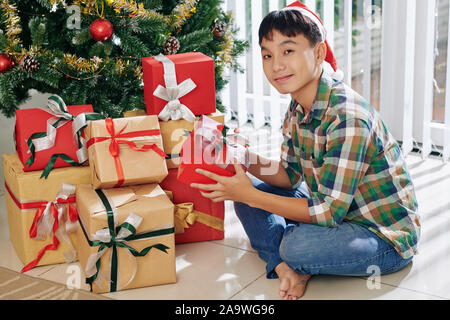 Sorridente adolescente ragazzo vietnamita godendo di aprire i regali di Natale sul Boxing day Foto Stock