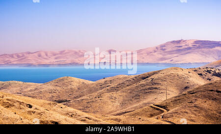 Angolo di alta vista di San Luis serbatoio, un lago artificiale di immagazzinare acqua per scopi agricoli in California centrale; colline ricoperte di erba secca in Foto Stock