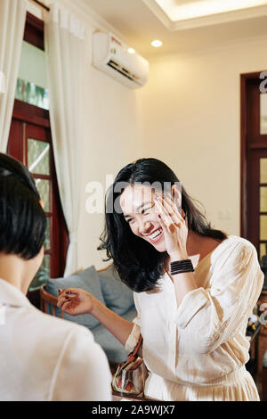 Ridendo giovane bella donna asiatica parlando a boutique hotel receptionist Foto Stock