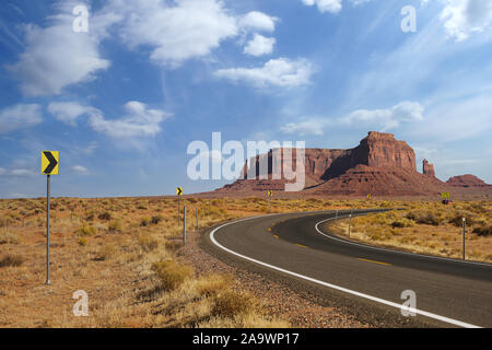 In autostrada in Monument Valley, Utah, Stati Uniti d'America - curva della strada che conduce verso le colline. Foto Stock