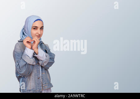 Piuttosto Arabian donna musulmana in abaya che mostra la forma di cuore con le mani, isolata. Emozioni positive, l amore, la cura e la salute del cuore di assicurazione sociale, Respons Foto Stock