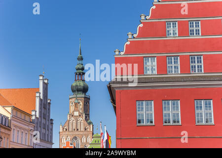 Red town hall e il campanile di una chiesa nella città anseatica di Greifswald, Germania Foto Stock