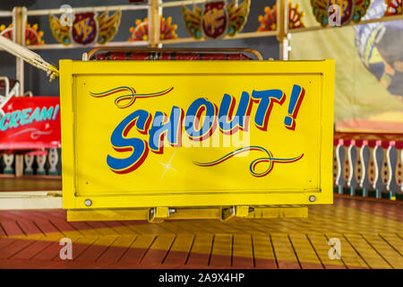 Un vivacemente colorato dipinto a mano fairground ride segno della parola gridare. Possibile concetto utilizza la perdita di udito, rabbia, attivismo farsi sentire. Foto Stock