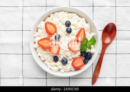 In casa cottage cheese, ricotta o tvorog con frutti di bosco freschi in vaso su sfondo tessili. Vista dall'alto. Caseificio sano prodotto, pulire il concetto di mangiare Foto Stock
