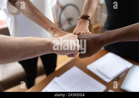 Close up multirazziale colleghi bumping pugni in riunione Foto Stock