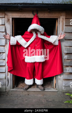 Uomo che indossa Santa Claus costume in piedi in un workshop porta. Foto Stock