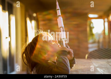 Un ragazzo giocando con un giocattolo Nasa Saturno 5 rocket, giorno sognando il volo spaziale. Foto Stock