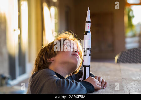 Un ragazzo giocando con un giocattolo Nasa Saturno 5 rocket, giorno sognando il volo spaziale. Foto Stock