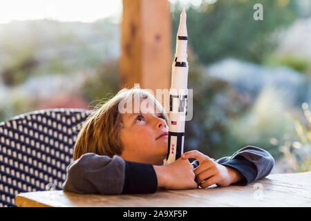 Un ragazzo giocando con un giocattolo Nasa Saturno 5 rocket, giorno sognando il volo spaziale. Foto Stock