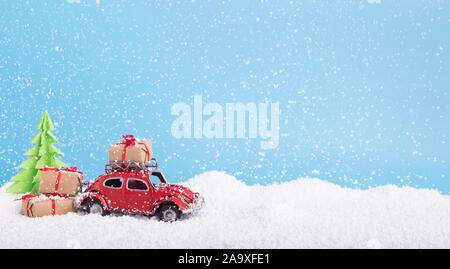 Giocattolo auto Volkswagen maggiolino con i regali di Natale e albero su blu Foto Stock