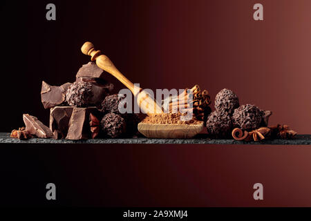 Tartufi di cioccolato con pezzi rotti di cioccolato e di spezie. Cioccolato, bastoncini di cannella e anice su uno sfondo scuro. Copia dello spazio. Foto Stock