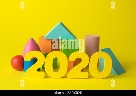 Background creativo realizzato in legno numeri 2020 e colorate forme geometriche su giallo minimo anno nuovo concetto. Foto Stock