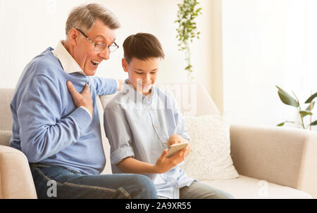 Ragazzo nonno di insegnamento per utilizzare Smartphone seduta sul lettino piscina Foto Stock