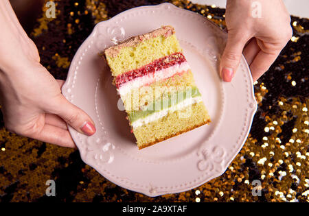 Golden brillante gustosa torta è tagliato a pezzi. Una fetta di torta su una piastra di rosa. In casa la cottura per una festa per i bambini. Foto Stock