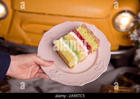 Golden brillante gustosa torta è tagliato a pezzi. Una fetta di torta su una piastra di rosa. In casa la cottura per una festa per i bambini. Foto Stock