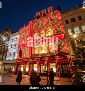 Luci festive in New Bond Street di notte con la facciata rossa di Cartier, Mayfair, Londra. Foto Stock