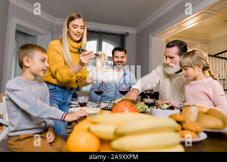 Bella famiglia avente una gustosa cena. Il cibo, la Giornata del ringraziamento e il concetto di tempo libero - famiglia mangiare pasta e deliziosa cena, giovane donna graziosa ho Foto Stock
