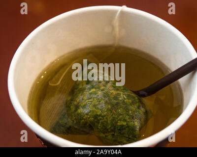 Tè del sacchetto di foglie di coca in acqua nel bicchiere di carta Foto Stock
