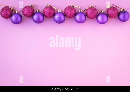 Le palle di Natale su sfondo rosa. Modello con copia spazio. Piatto, laici anno nuovo mockup. Viola sfere lucido. Foto Stock