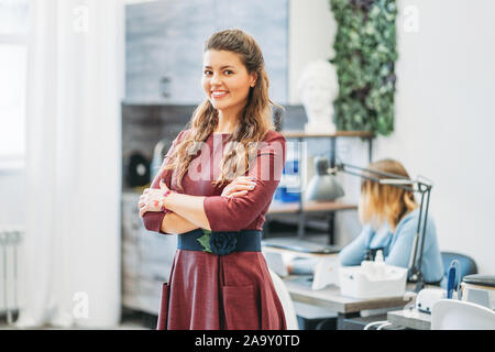 Affascinante giovane donna sorridente proprietario del salone di bellezza nail bar, il concetto di una piccola impresa Foto Stock