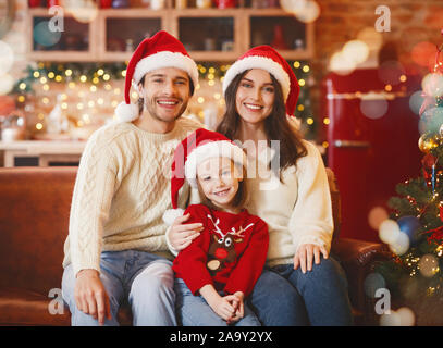 Warm giovane famiglia ottenere pronto per Natale, seduto sul divano Foto Stock