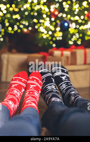 Primo piano della giovane i piedi nelle calze di Natale vicino albero di Natale Foto Stock