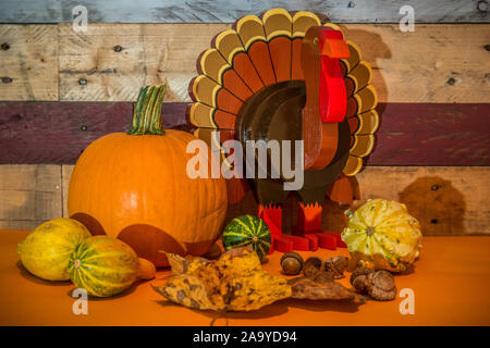 Un ringraziamento vacanza display con una zucca zucche Foglie di autunno e ghiande e un artigianato artistico del legno della Turchia contro un pallet rustico sfondo a parete Foto Stock