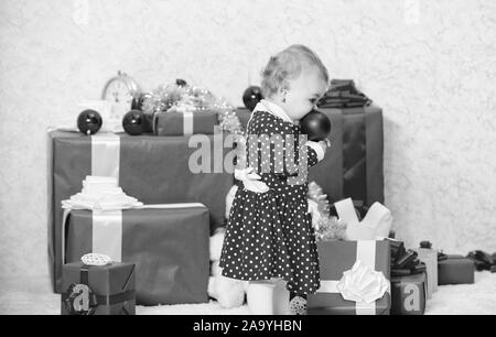 Doni per i bambini prima di natale. Little Baby girl giocare vicino a pila di confezioni regalo. Vacanza in famiglia. Attività di Natale per i bambini piccoli. Regali di natale per bambino. Cose da fare con i bambini a Natale. Foto Stock