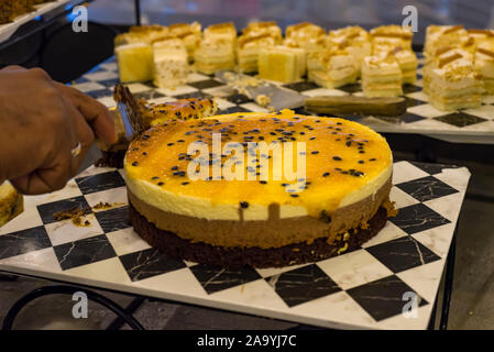 Close-up di delizioso pezzo di cheesecake condito con salsa di caramello su un sfondo rosa gialla torta dolce Foto Stock