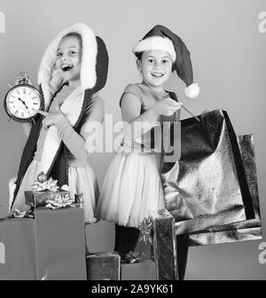 I ragazzi di Santa Claus cappelli aprire dono scatole e confezioni. Le ragazze aspettare per il nuovo anno puntando alla sveglia. Festeggiando e concetto di vacanza. I bambini con facce felici giocare su sfondo blu. Foto Stock