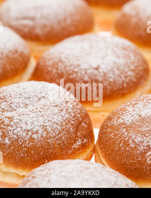 Sfondo di molti Krapfen e rabboccato con zucchero a velo fianco a fianco insieme Foto Stock