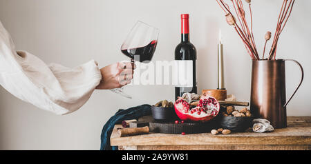 Womans mano che tiene un bicchiere di vino e snack, ampia composizione Foto Stock